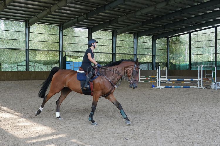 障碍训练场上骑马的年轻女子