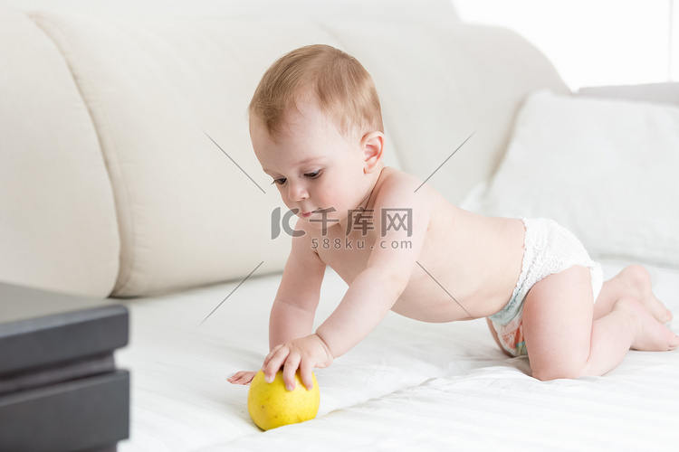 可爱的宝宝爬在床上，伸手去拿苹