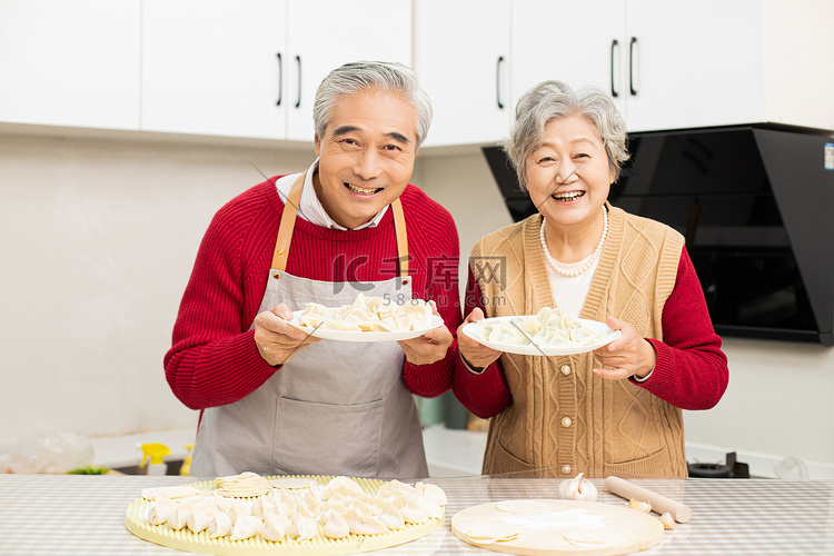 夫妻两在厨房手端着饺子微笑摄影