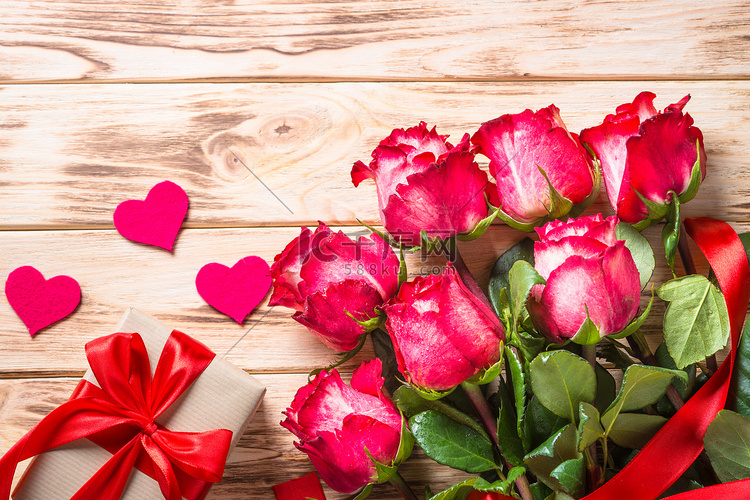 木桌上的红玫瑰花和礼物盒. 
