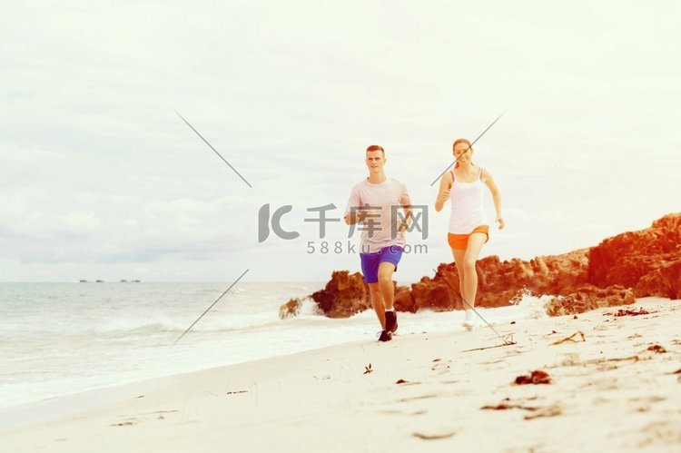 跑步者。一对年轻夫妇在海滩上奔
