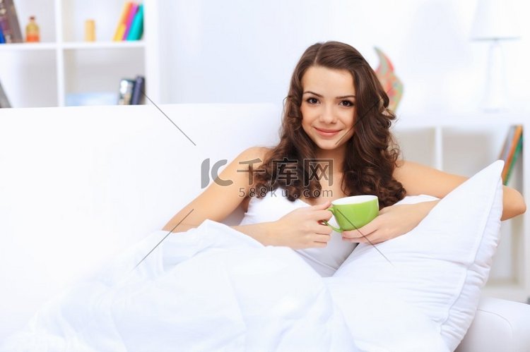 可爱的年轻女子在家喝茶的写真