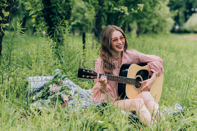 快乐的妇女在太阳镜与声学吉他休