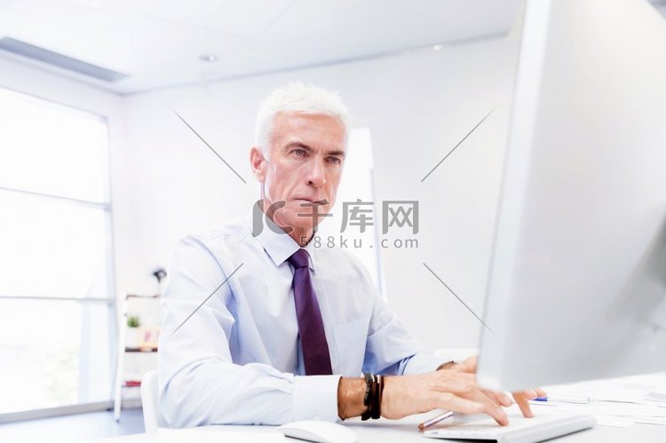 坐在办公室里用电脑工作的商人。