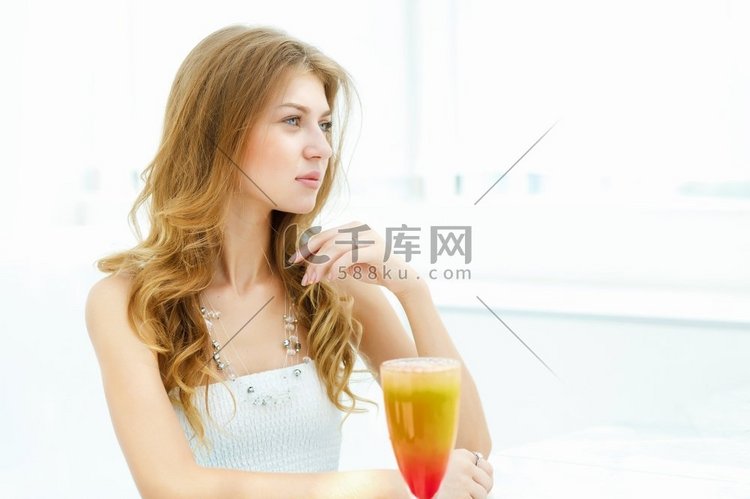 年轻美丽的女人与一杯饮料坐在咖