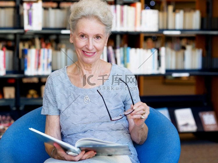 一位老妇人在图书馆看书。从容地