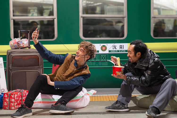 两名男子在火车月台上看手机
