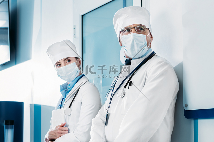 医用口罩中的男、女医生站在医院