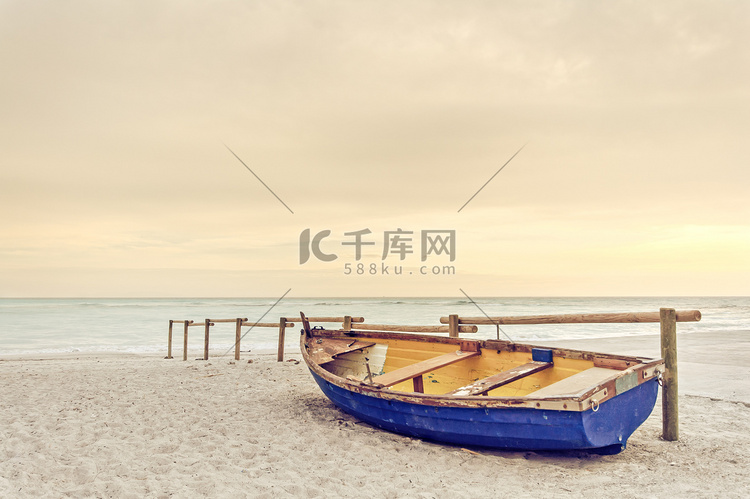 老黄蓝色木质小船在白色的沙滩上