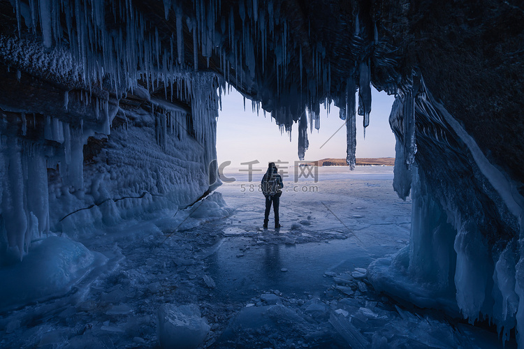 一名男子站在贝加尔湖冰洞前的冰