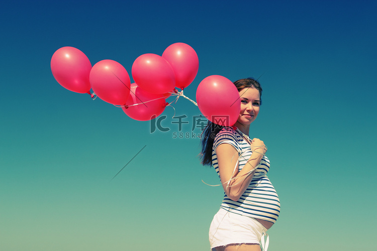 unga gravid kvinna med röda ballonger