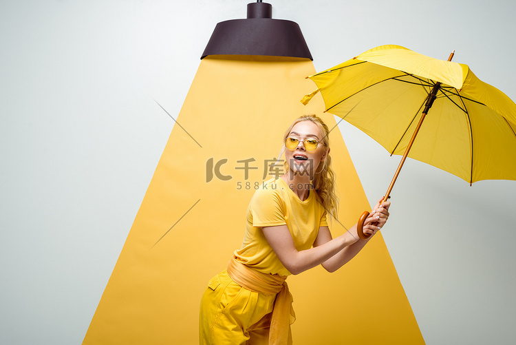 开朗的金发女孩在太阳镜拿着伞在