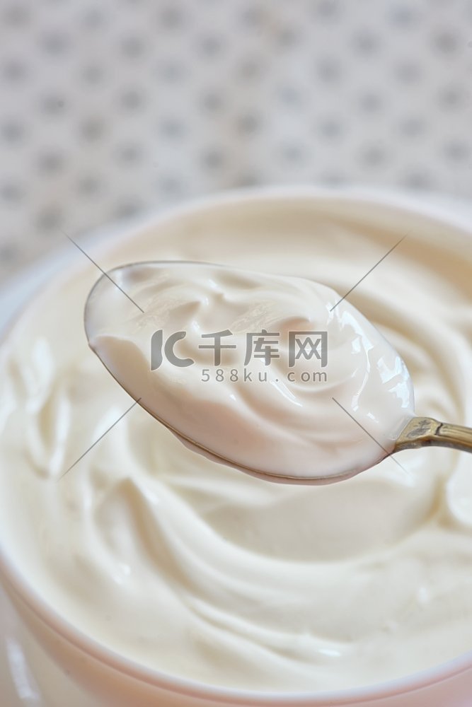 用勺子盛白酸奶的陶瓷碗