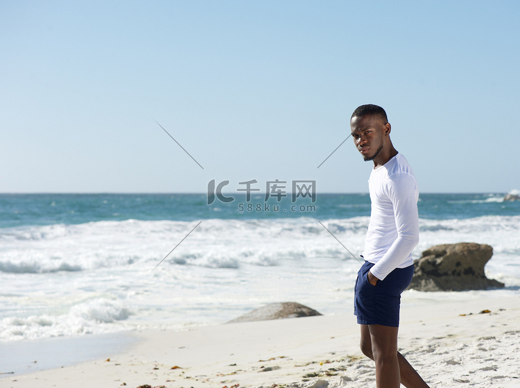 英俊的年轻男子，独自站在沙滩上
