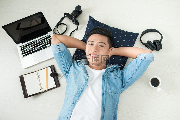 男子躺在地板上，笔记本电脑