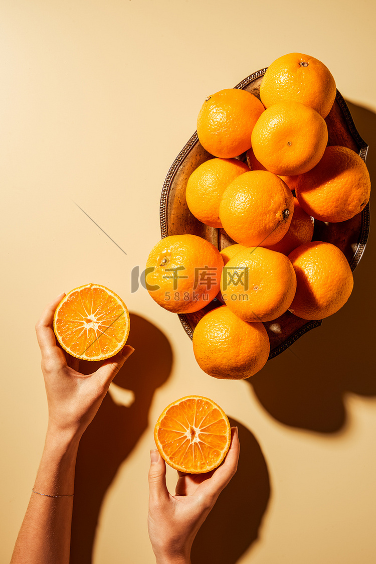用金属碗将橘子半放在米色背景上