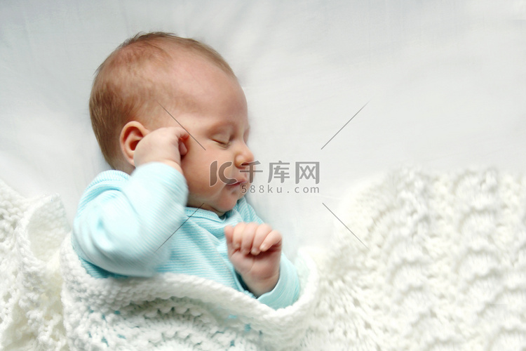 在白色的毯子里熟睡的刚出生的婴