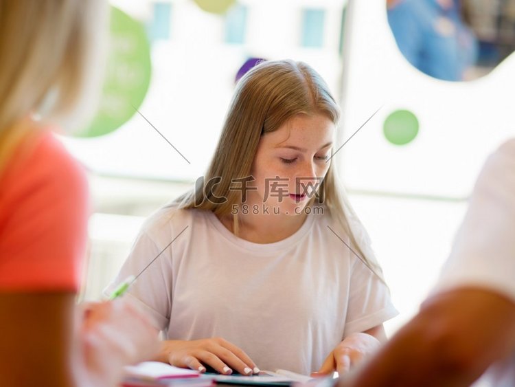 十几岁的女孩拿着书在图书馆学习