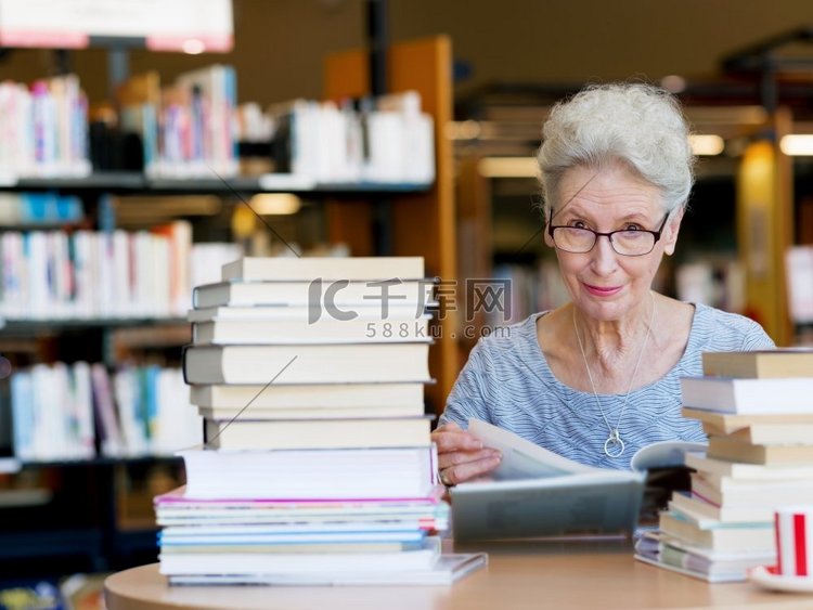 一位老妇人在图书馆看书。从容地