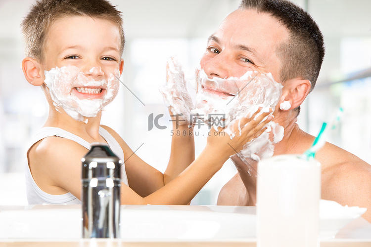 快乐的孩子跟爸爸用剃须泡沫在浴