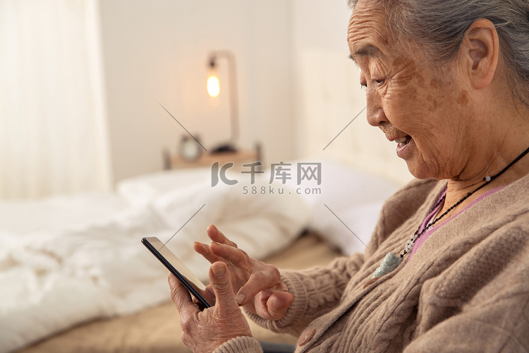 老年人坐在床上看手机