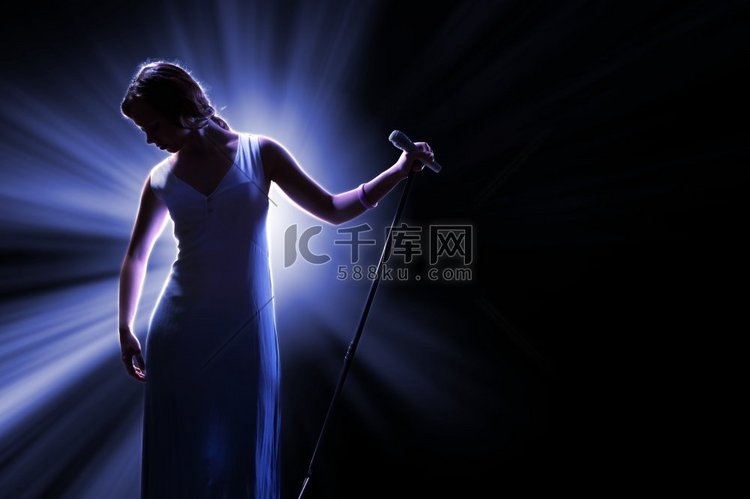 女歌手在舞台上拿着麦克风。舞台