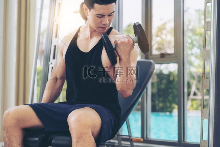 肌肉男健美健身房训练哑铃。健康