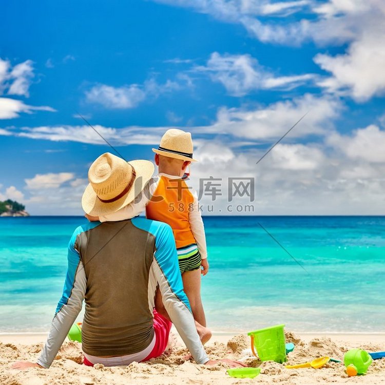 三岁的小男孩和父亲在海滩上。夏