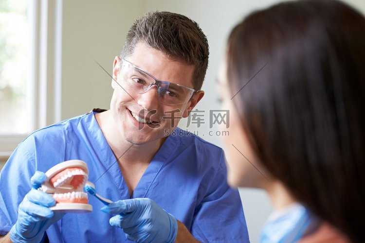 牙医向女客户示范正确使用牙刷