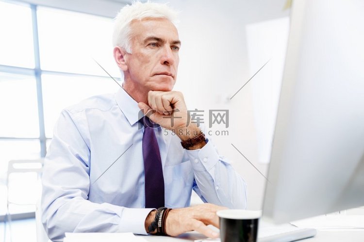 坐在办公室里用电脑工作的商人。