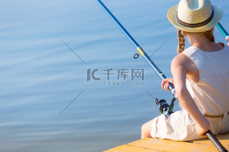 女孩穿着裙子，戴着一顶带钓鱼竿