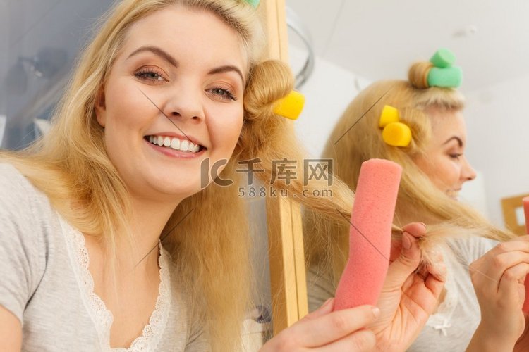 一位金发女子用卷发机在她的发型