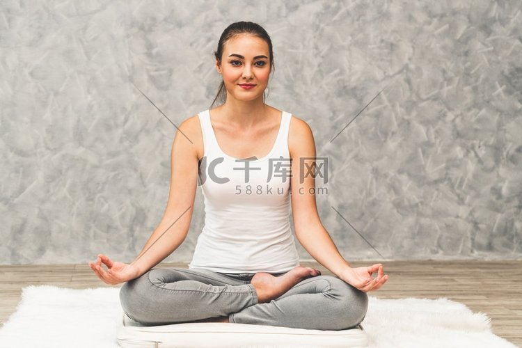 年轻漂亮的女人做瑜伽练习在地毯