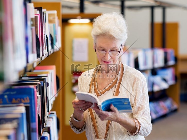 一位老太太站在图书馆的书架旁。