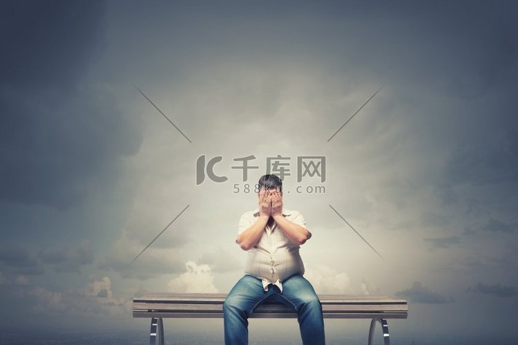 坐在板凳上的胖子用手闭着眼睛。