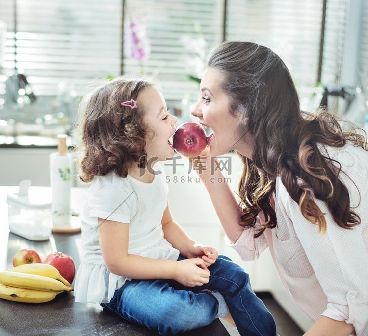 母亲和欢快的女儿咬苹果