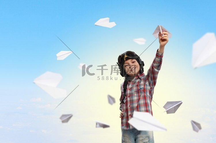 戴着飞行员头盔的小男孩在玩纸飞