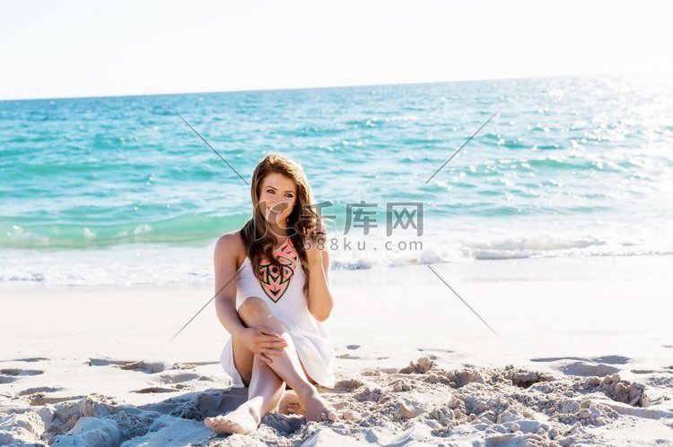 坐在海滩上的年轻女子。坐在沙滩