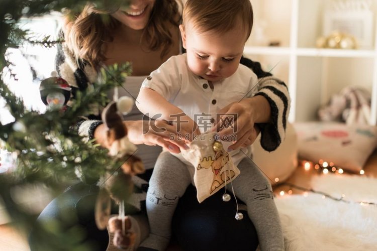 母亲和蹒跚学步的孩子装饰圣诞树