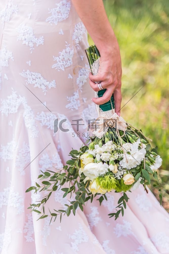 新娘手中的婚礼花束在礼服的背景