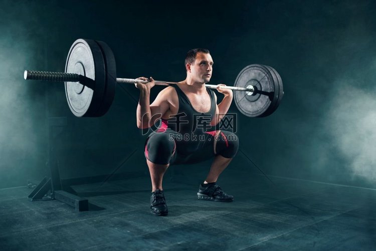 举重运动服做蹲与杠铃在健身房。
