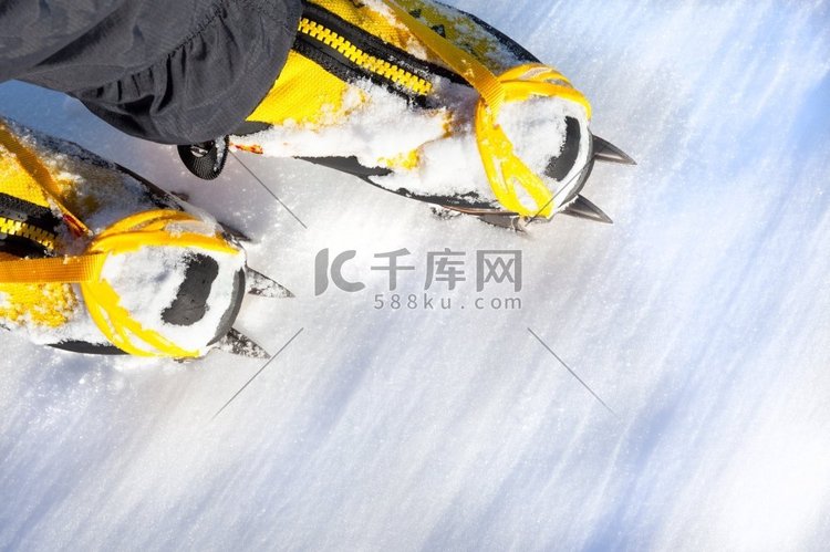 一双雪地里有冰爪的黄色高山靴子