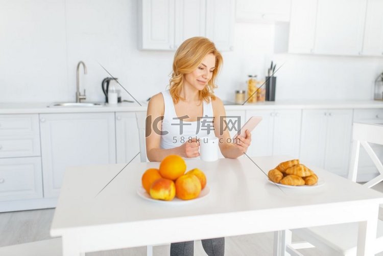 快乐的女人在桌子上的水果和烘焙