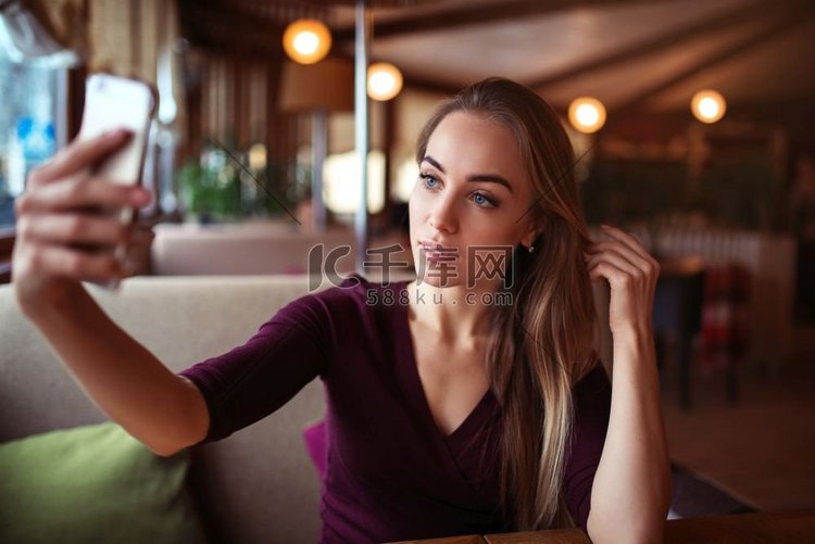 年轻漂亮的女人在餐馆自拍。