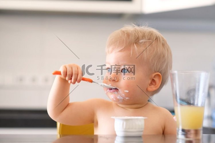 可爱的一岁男孩用勺子吃酸奶。肮