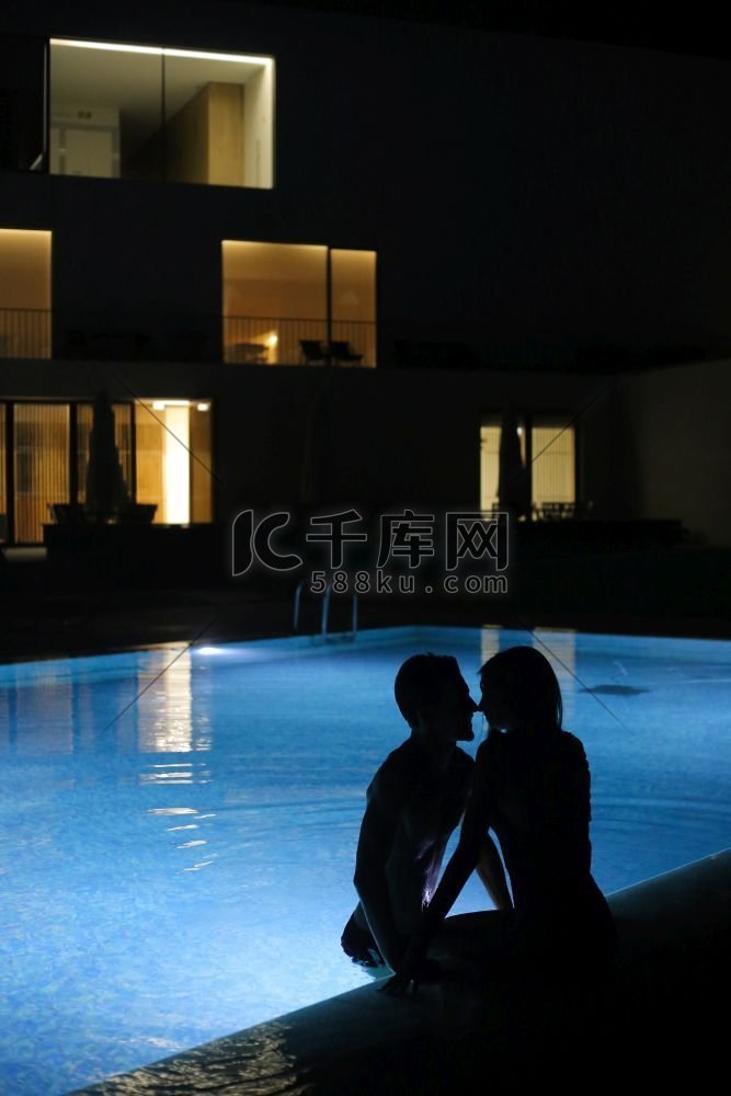 浪漫的夫妇接吻在游泳池在晚上—