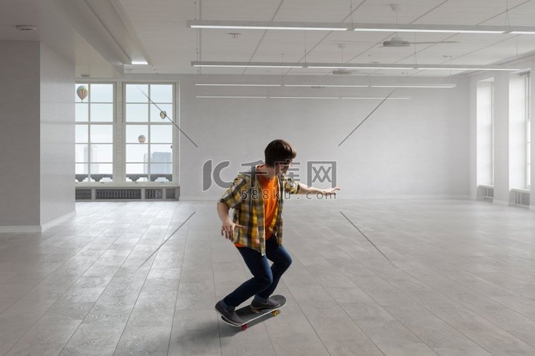 男孩骑滑板。在现代室内玩滑板的