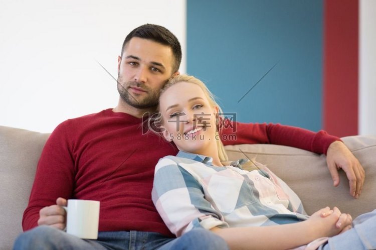 幸福的年轻夫妇在家里的沙发上拥