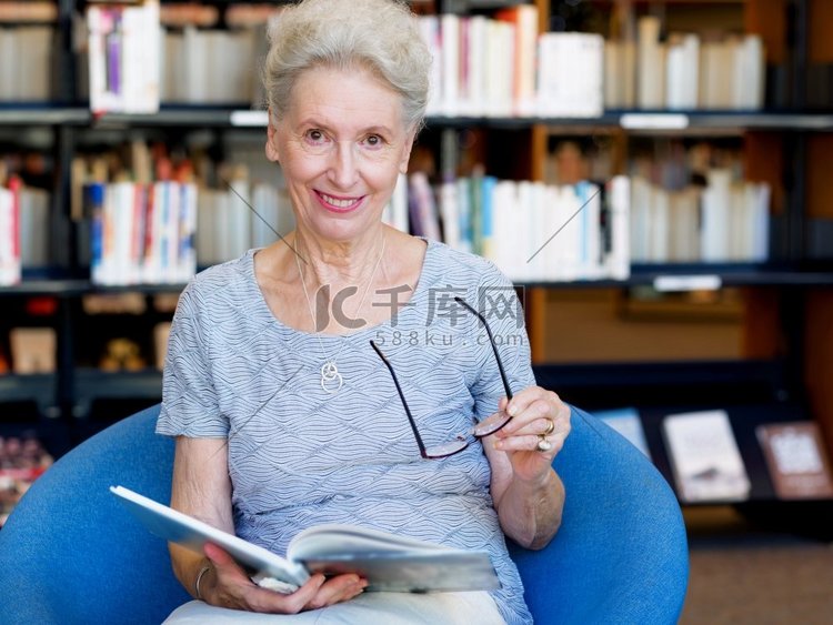 老太太在图书馆看书。花时间读新