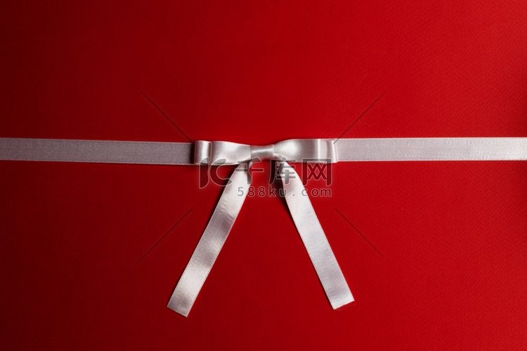 白色缎子丝带蝴蝶结在红纸背景。